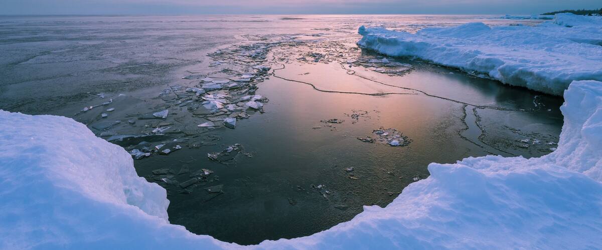 A frozen river with ice floes and snowbanks.