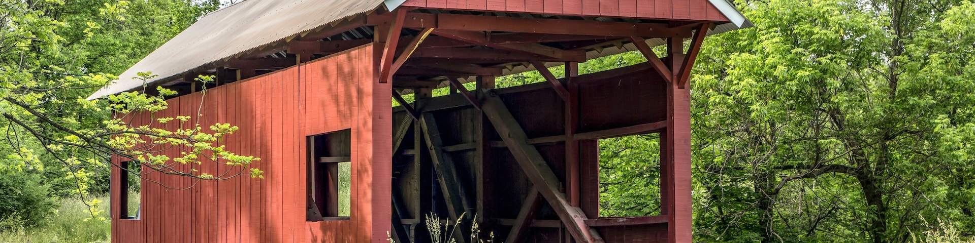 The historic red Erskine Covered Bridge crosses Middle Wheeling Creek in rural wooded Washington County, Pennsylvania.