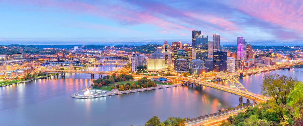 A cityscape with a river, a bridge, and a variety of buildings including skyscrapers.