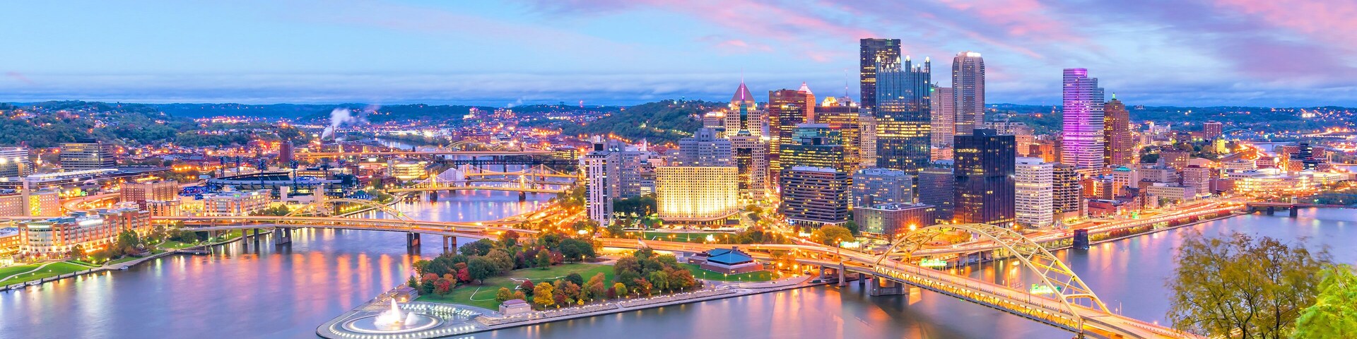 A cityscape with a river, a bridge, and a variety of buildings including skyscrapers.