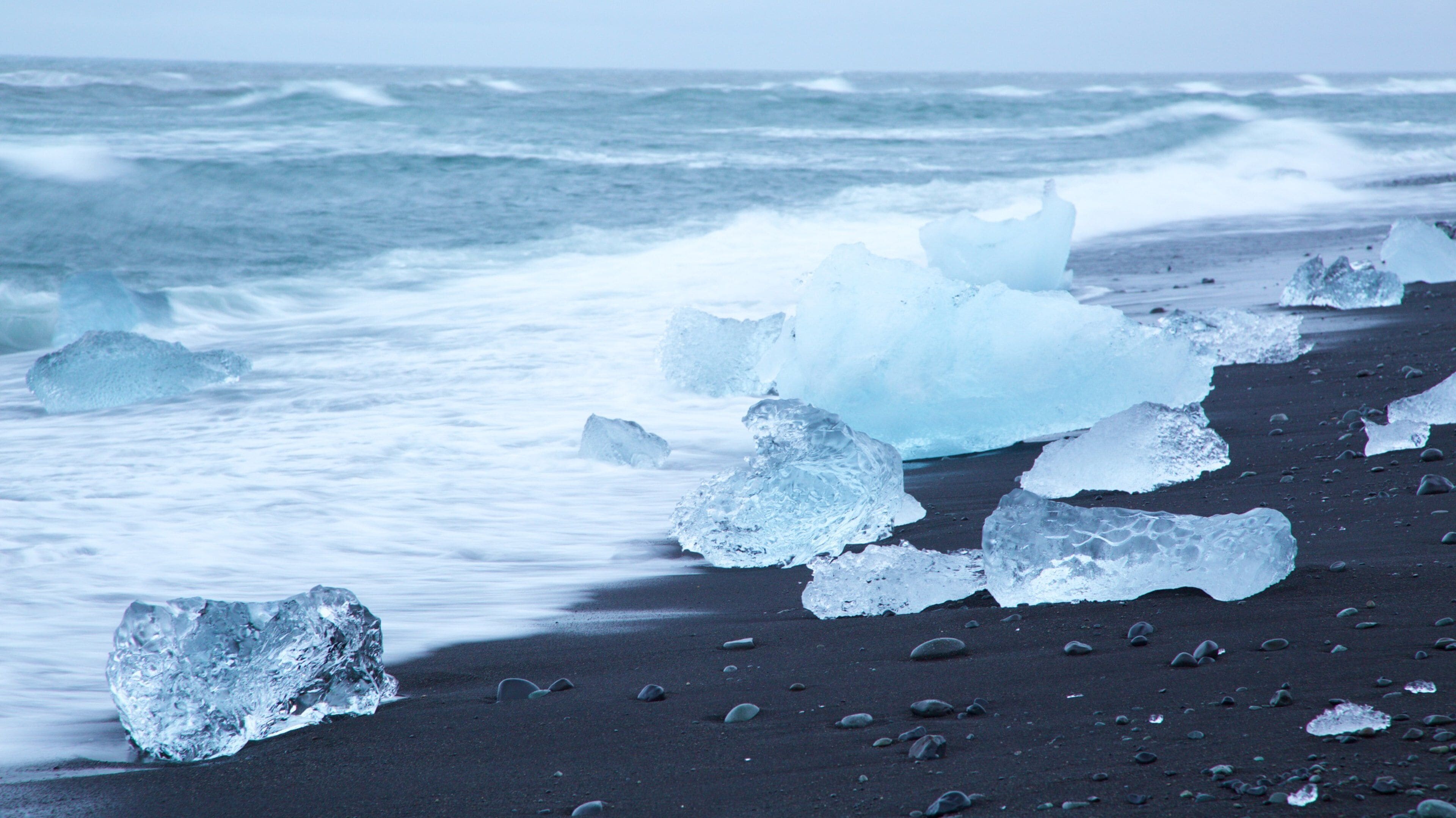 Icebergs en una playa con el océano al fondo.