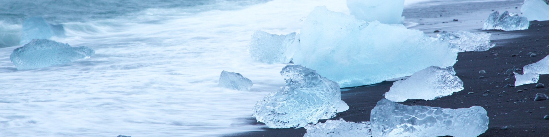 Icebergs en una playa con el océano al fondo.