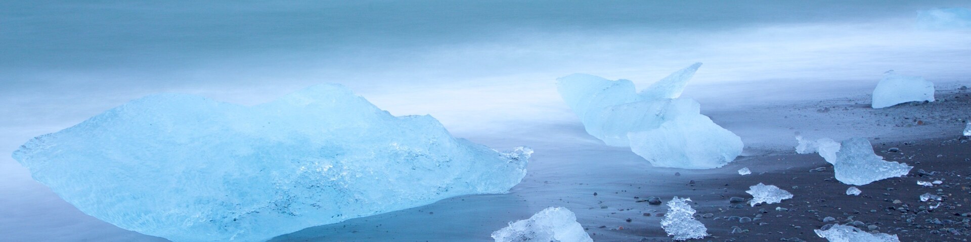 Una playa con icebergs grandes y fragmentos de hielo más pequeños dispersos.