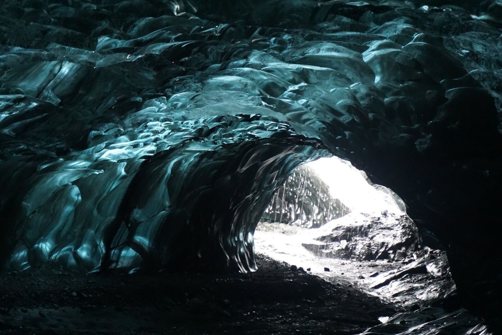 An ice cave with a narrow opening allowing light to enter.