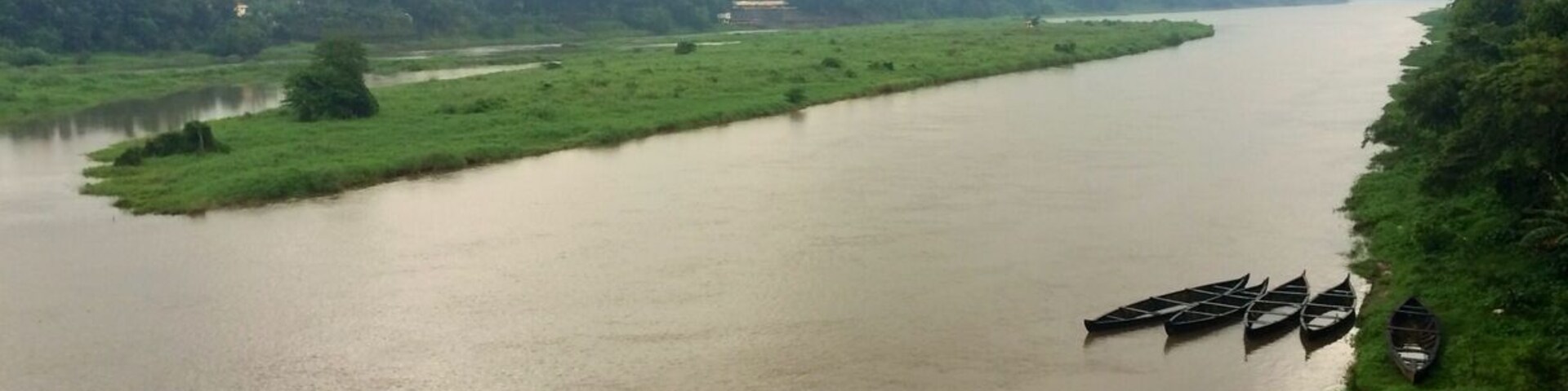 A river with boats docked on the right bank.