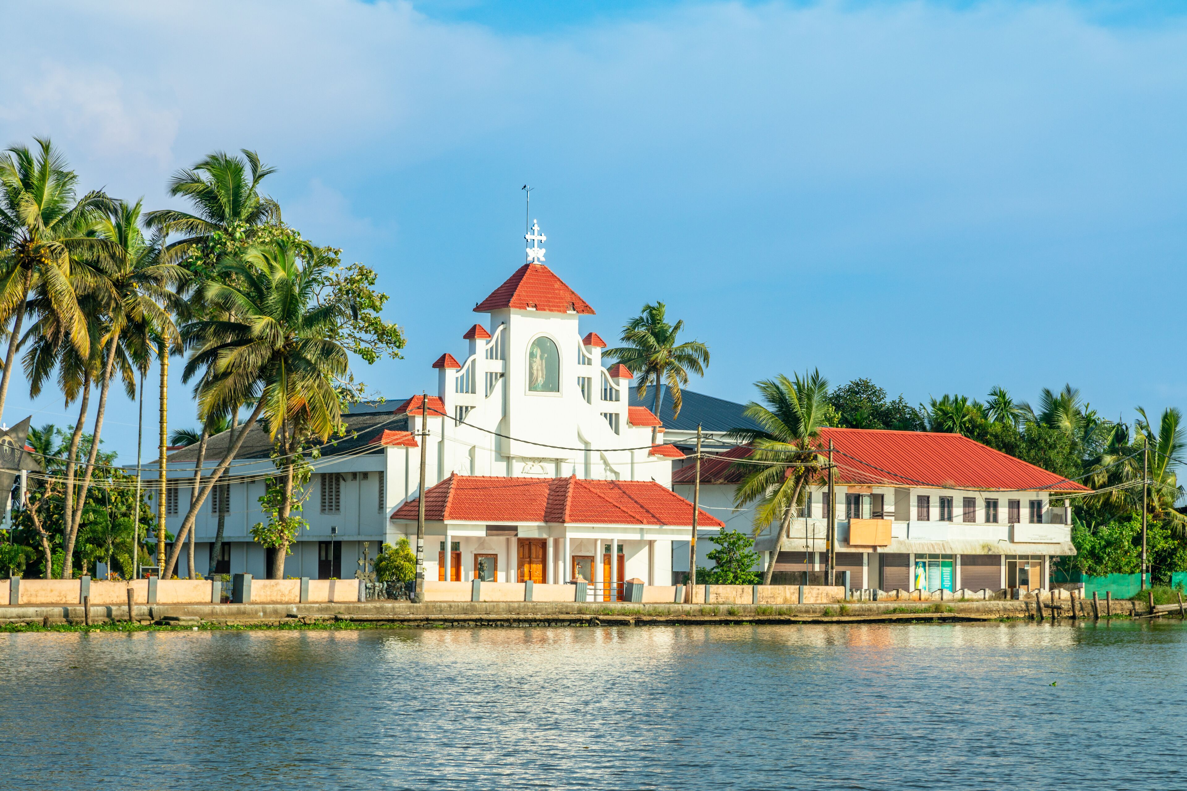 Old colonial Saint Thomas catholic church on the coast of Pamba river, with palms, Alleppey, Kerala, South India