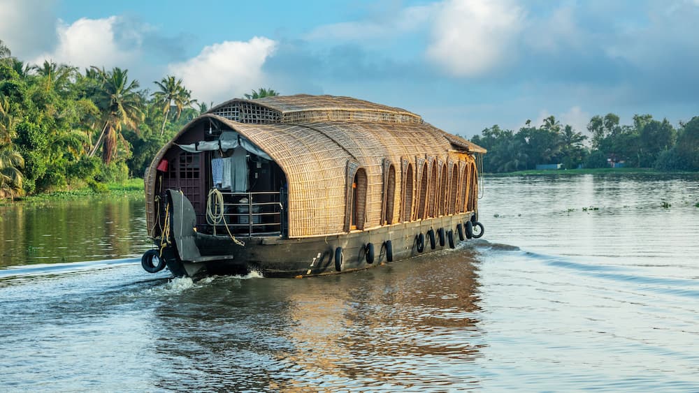 Indian traditional houseboats floating on Pamba river, with palms at the coastline, Alappuzha, Kerala, South India