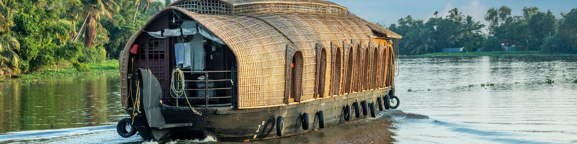 Indian traditional houseboats floating on Pamba river, with palms at the coastline, Alappuzha, Kerala, South India