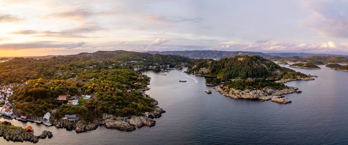 A coastal landscape with multiple islands, rocky shores, and a village with red-roofed houses.