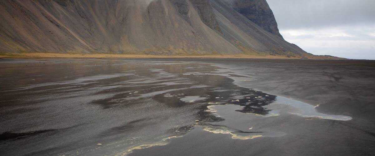 A barren landscape with a large mountain partially obscured by clouds.