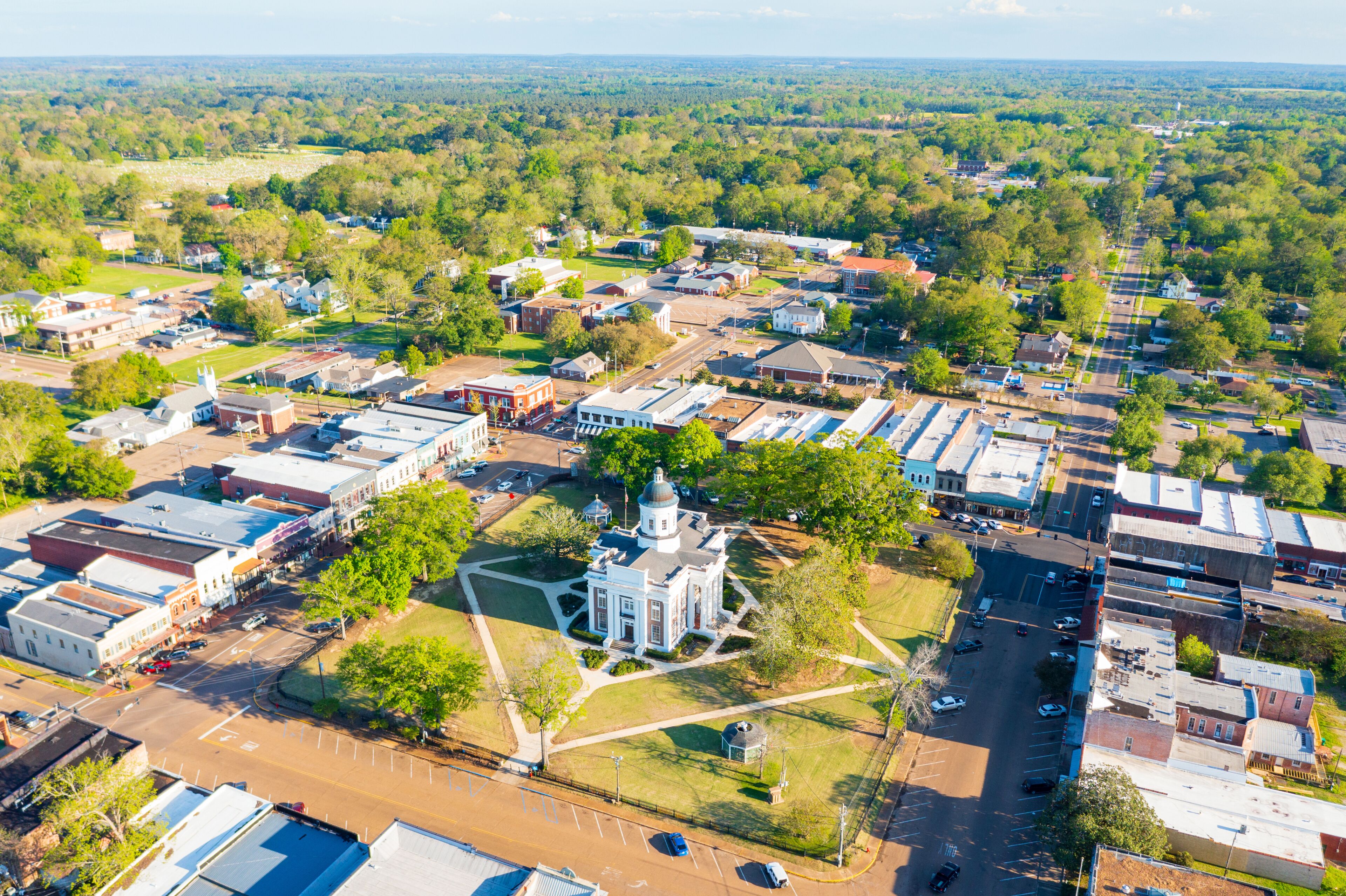 An aerial view of a town with a prominent church, wide streets, and surrounding greenery.