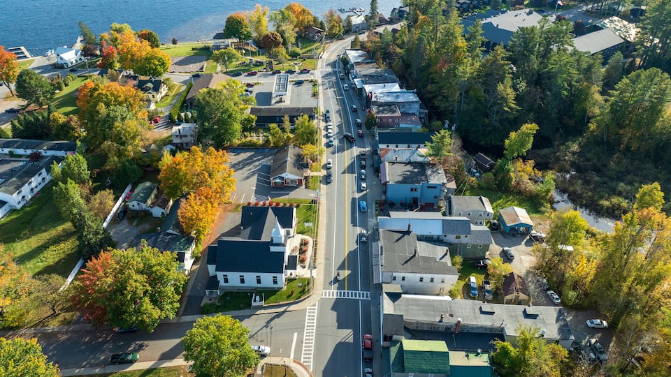 An aerial view of a residential area with houses, a road, and a body of water.