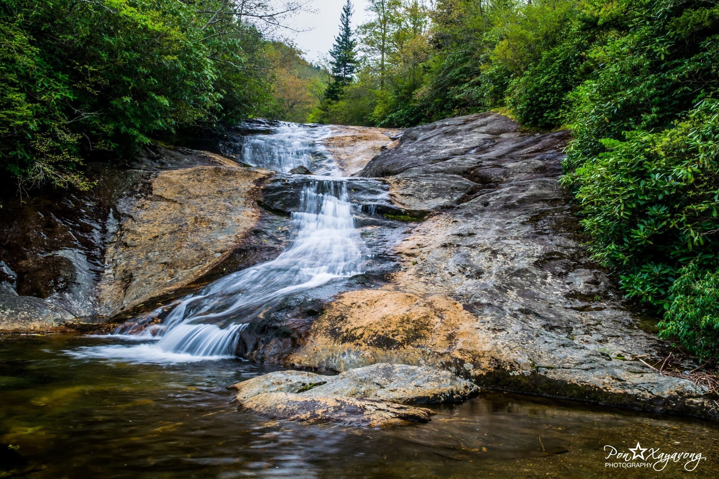 A waterfall cascading over rocks in a forested area.