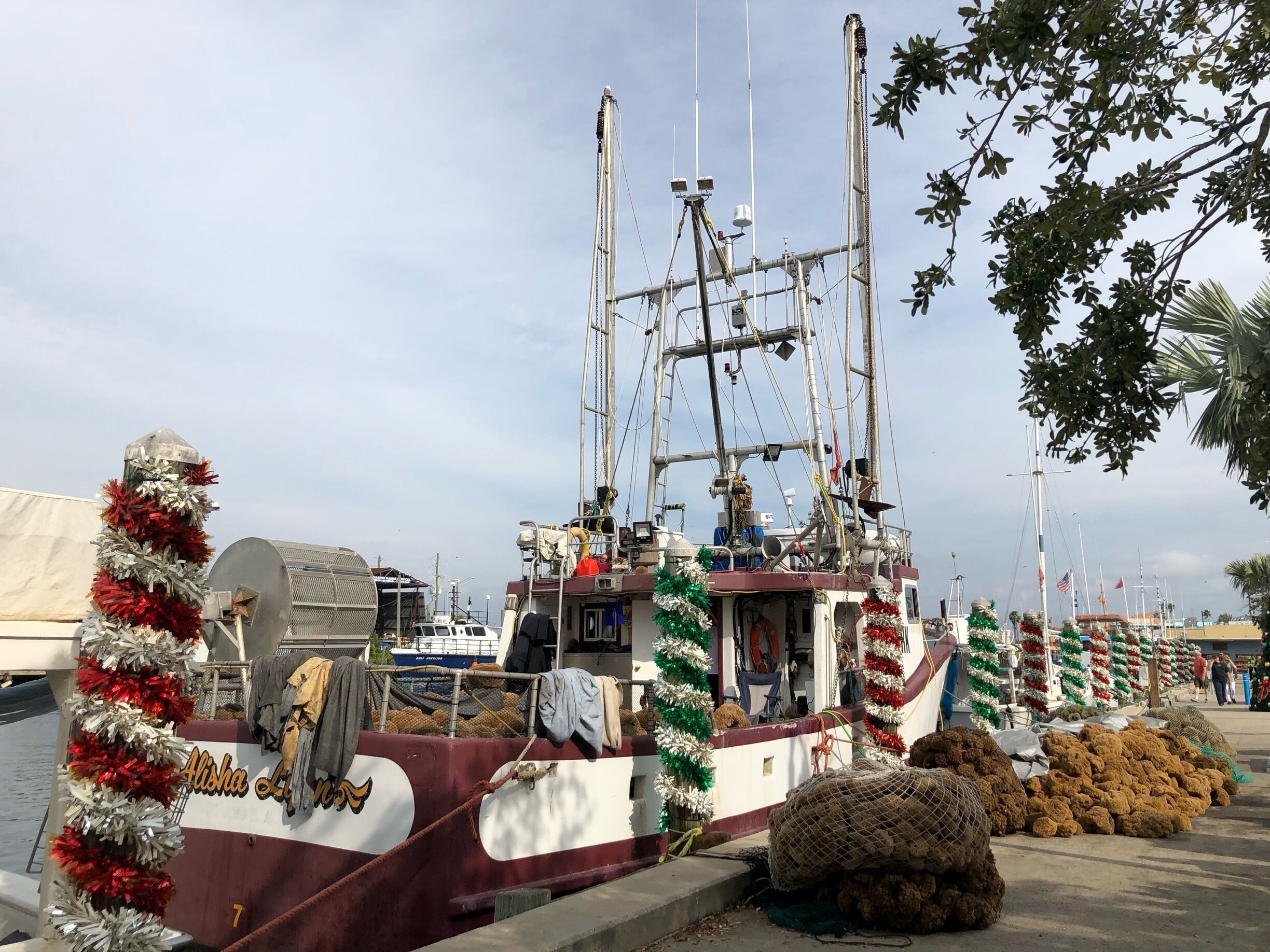 A boat docked at a marina with festive decorations and fishing nets.