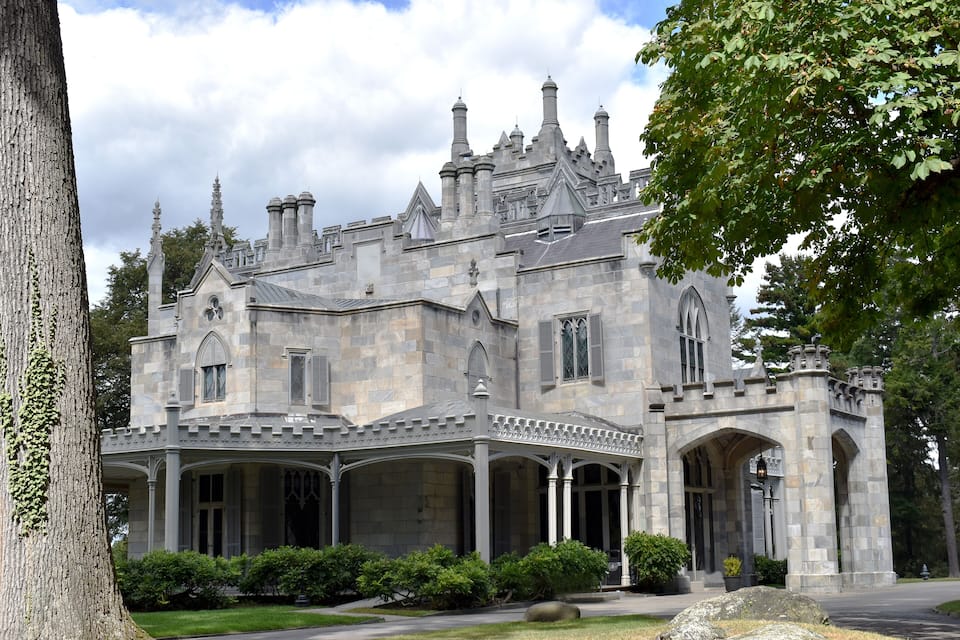 A large, historic stone building with multiple chimneys and arched windows.