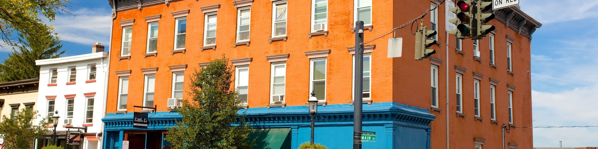 A red brick building with blue trim, a green SUV, and a red car parked in front.