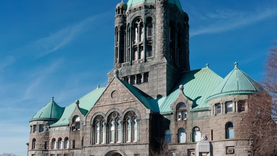 A large stone building with a green dome and arched windows.