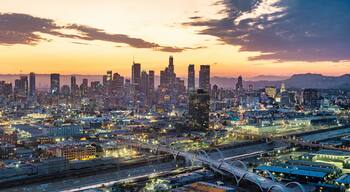 A city skyline at dusk with illuminated buildings and a bridge.