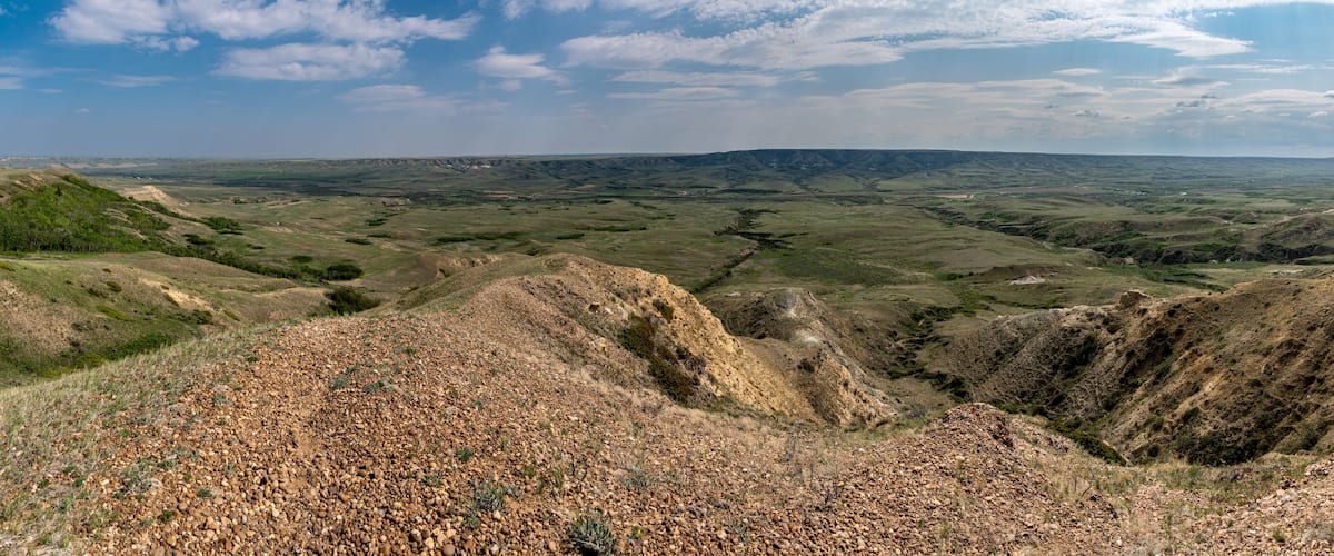 A vast landscape with rolling hills, a valley, and a clear sky.