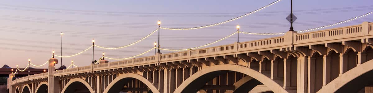 Eine Brücke mit mehreren Bögen über einem Gewässer, beleuchtet mit Lichterketten.