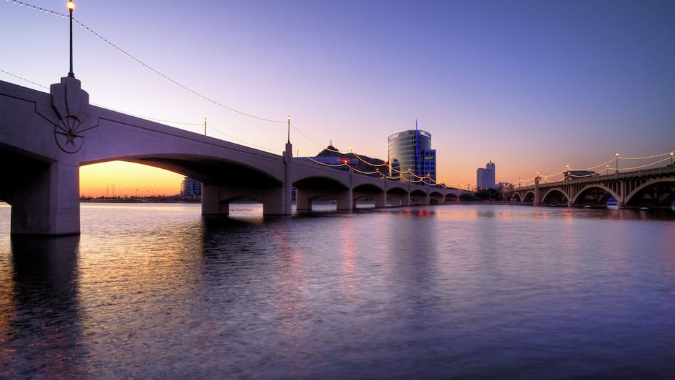 A bridge over a body of water with a sunset in the background.