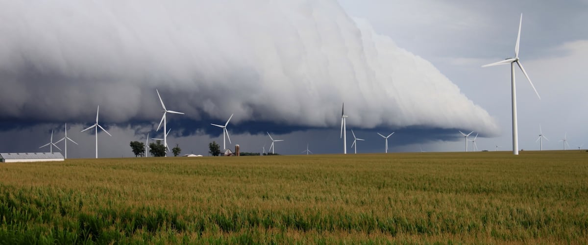A field with wind turbines under a stormy sky.