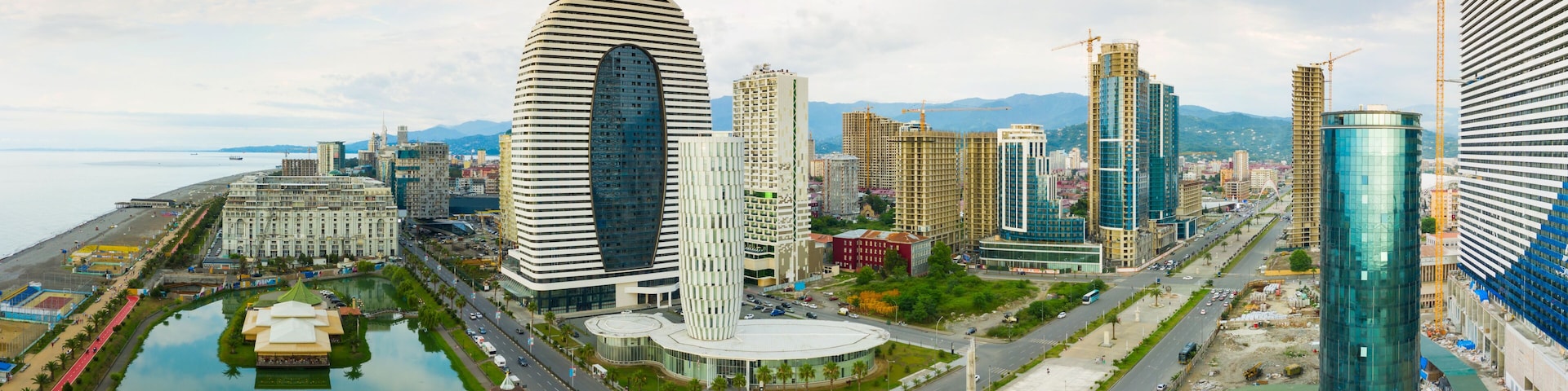 A cityscape with modern buildings, a waterfront, and a large roundabout.