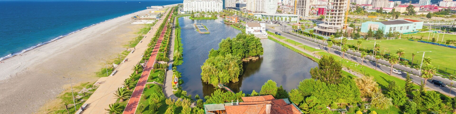 Paisagem costeira com rio, praia e edifícios modernos.