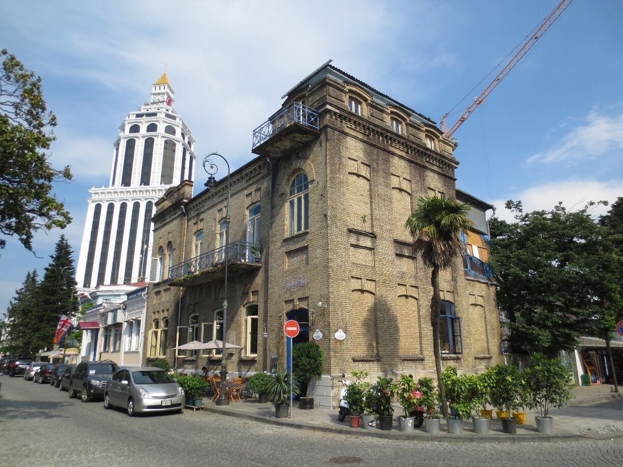 Old and new - view an old brick building in the Black Sea coastal city of Batumi, Georgia.

Construction crane and modern tower in the background.  