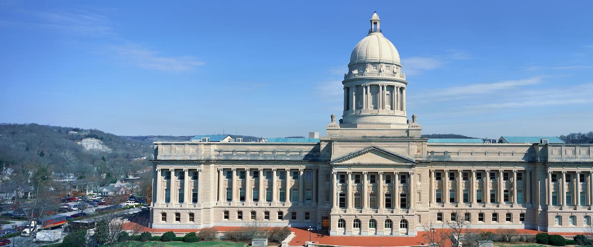 A large neoclassical building with a central dome and columns, surrounded by a hilly landscape.