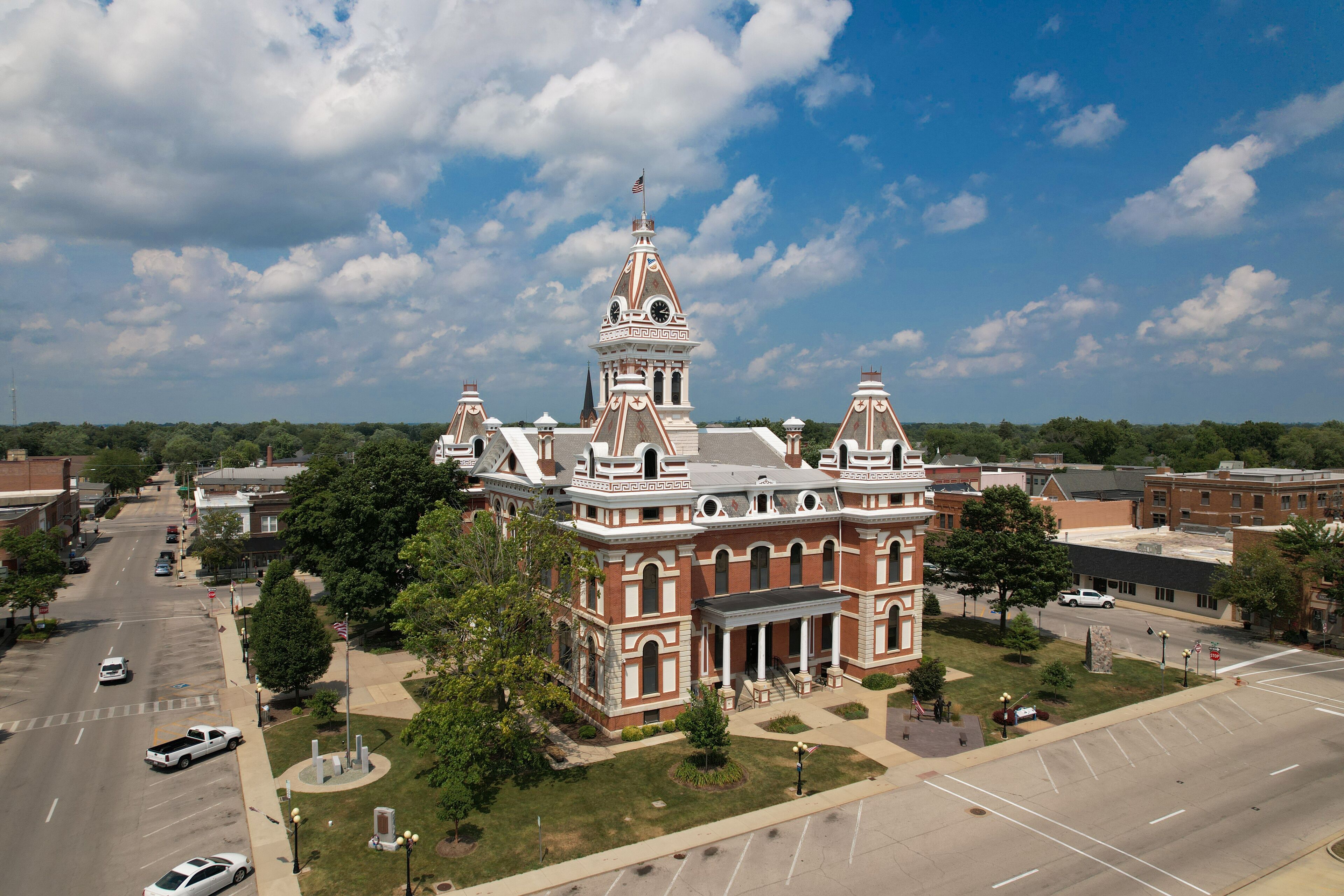 A large, historic building with a prominent tower and columns, surrounded by a parking lot and a street.