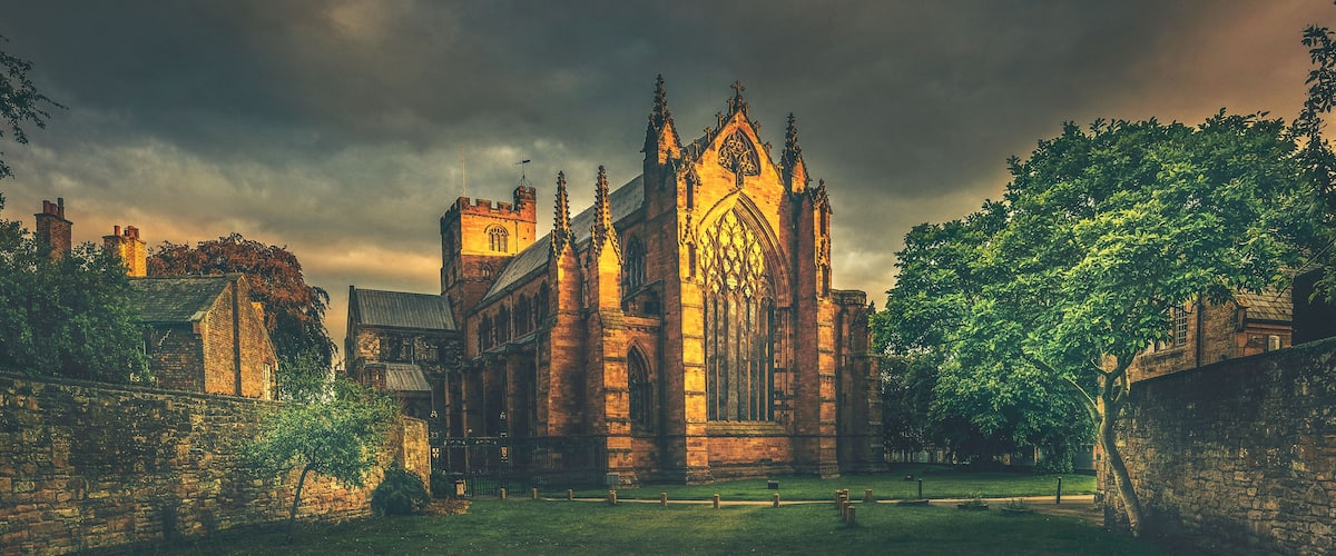 A historic church with Gothic architecture, surrounded by stone walls and trees.