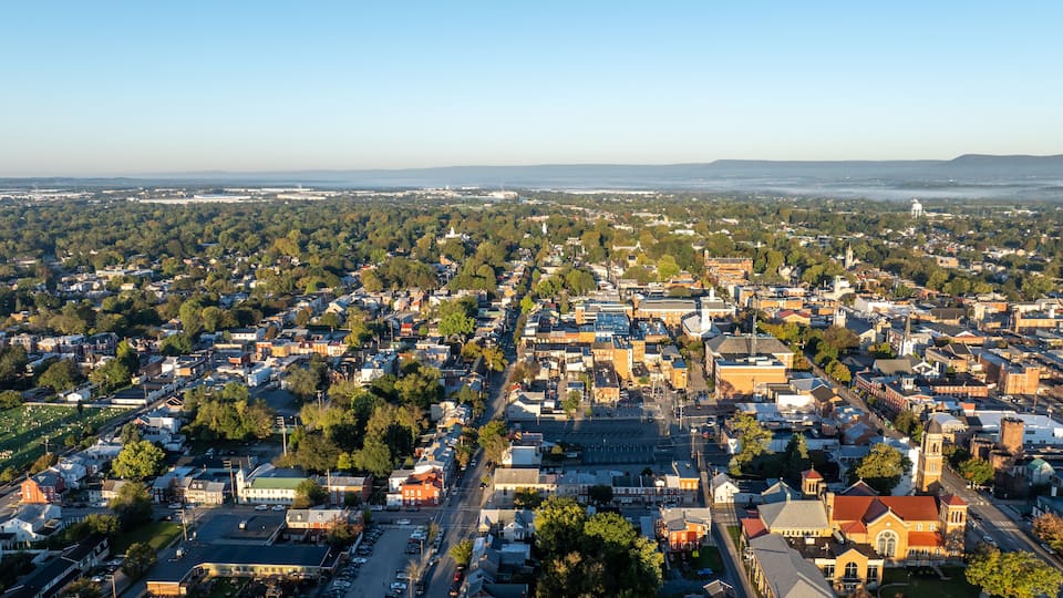 Aerial view of Carlisle, PA, showcasing a mix of residential, commercial buildings, and tree-lined streets under a clear morning sky.