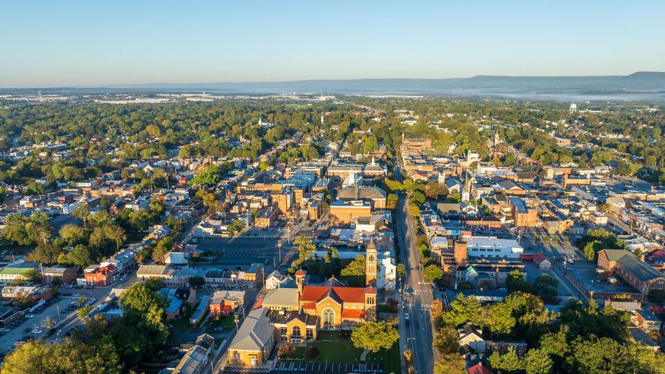 Aerial view of Carlisle, PA, showcasing a mix of residential, commercial buildings, and tree-lined streets under a clear morning sky.