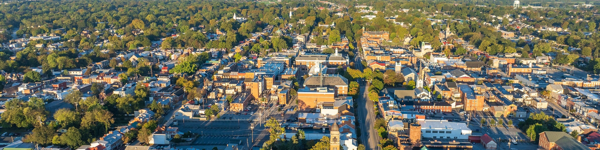 Aerial view of Carlisle, PA, showcasing a mix of residential, commercial buildings, and tree-lined streets under a clear morning sky.