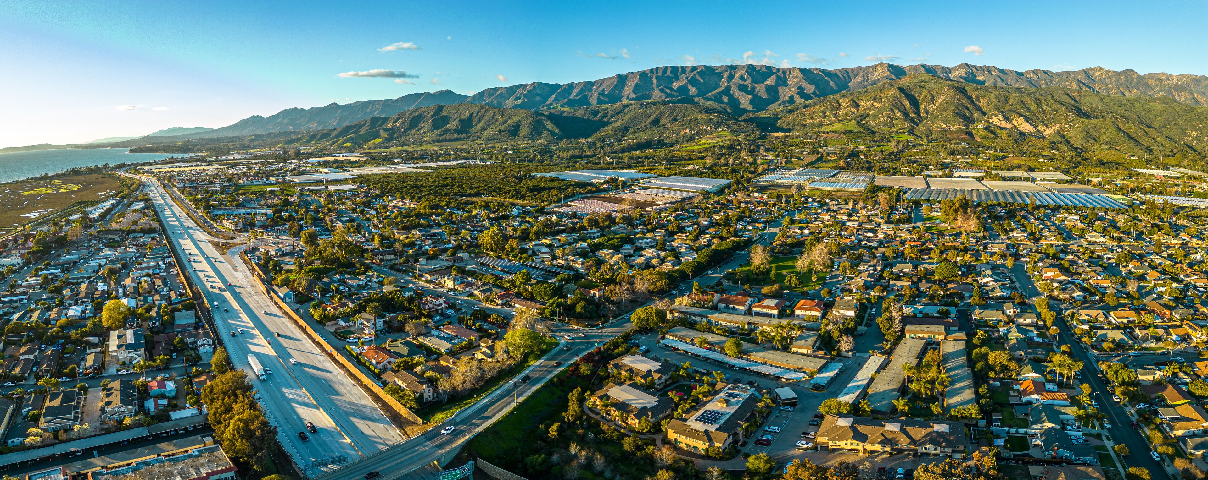 An aerial view of a coastal town with residential areas, roads, and solar panels.