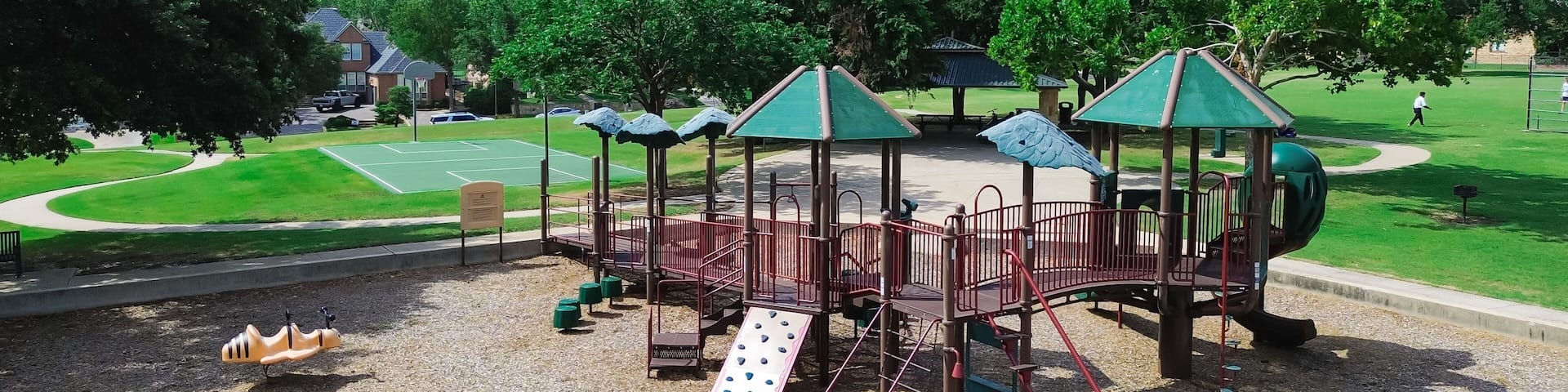Panorama view upscale suburban houses near community park with playground, hopper fun bouncer string rider, basketball courts, baseball softball field backstop netting, West Plano, Texas, aerial