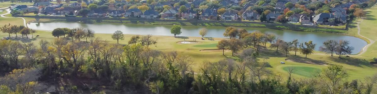 Top view country club golf course and lakeside residential houses near nature park with fall foliage in Carrollton, Texas, USA