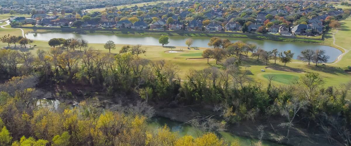 Top view country club golf course and lakeside residential houses near nature park with fall foliage in Carrollton, Texas, USA