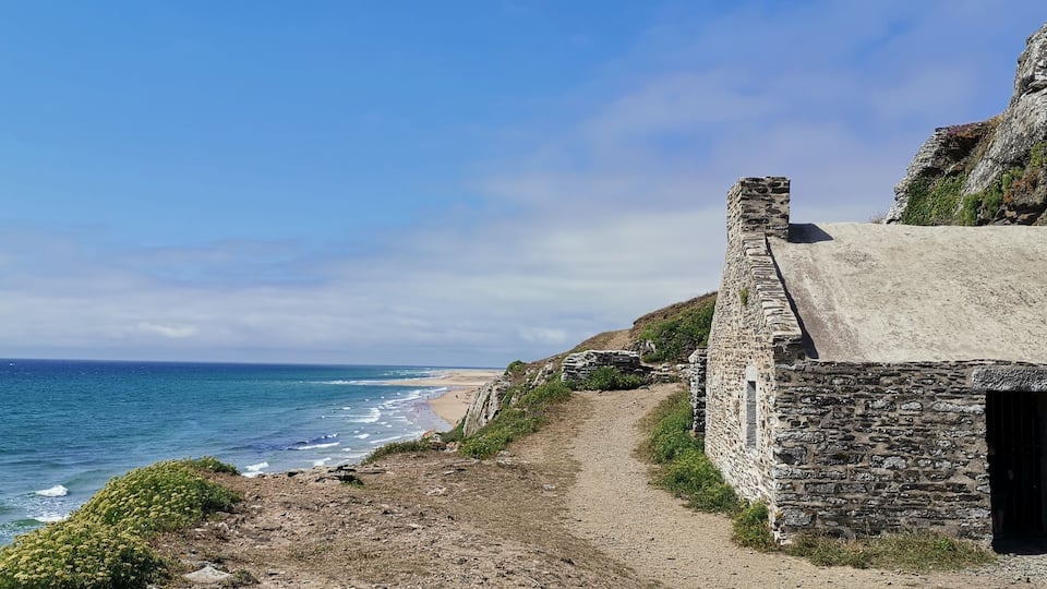 A coastal path leading to a stone building by the sea.