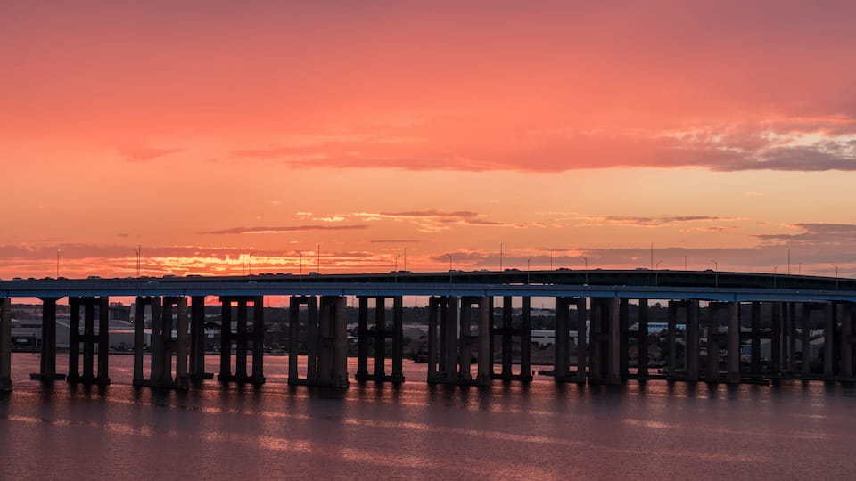 A sunset over a bridge with water below.
