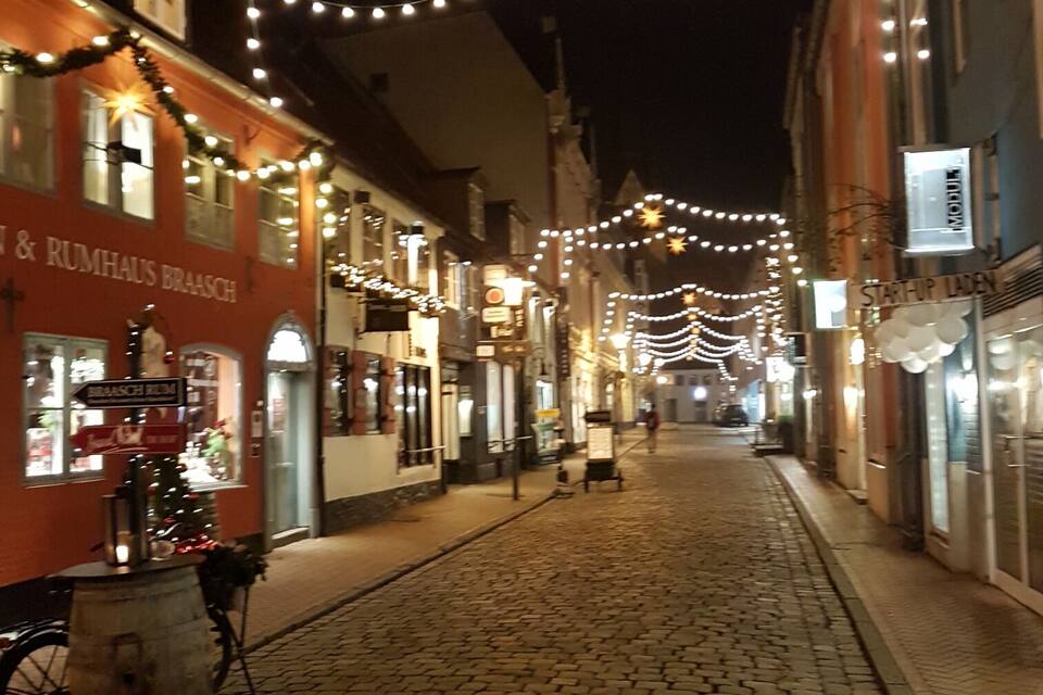 Eine Kopfsteinpflasterstraße bei Nacht mit Lichterketten und einer Sterndeko.