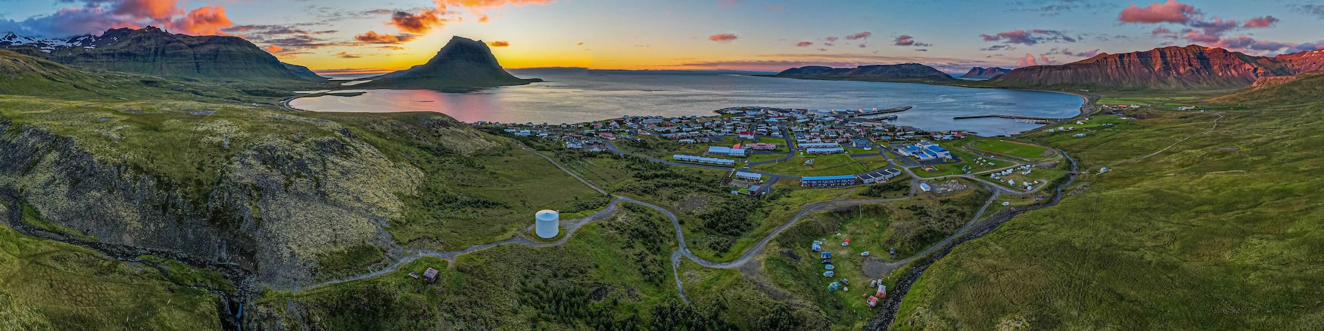 Flateyri village in Iceland Westfjords aerial panorama at sunset with colorful clouds calm fjord waters and dramatic surrounding mountains