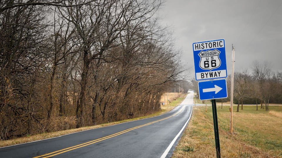 A road with a blue sign indicating Historic Missouri US 66 Byway.