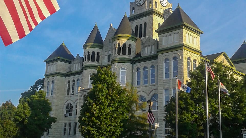 A historic building with a clock tower, flags, and an American flag.