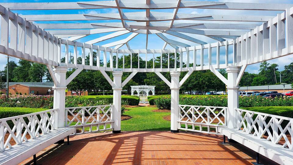 A white gazebo with a glass roof in a park.