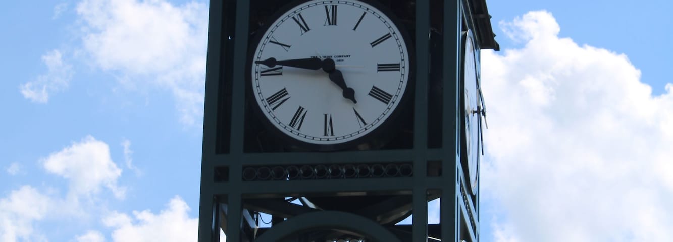 A clock tower with Roman numerals and a weather vane on top.