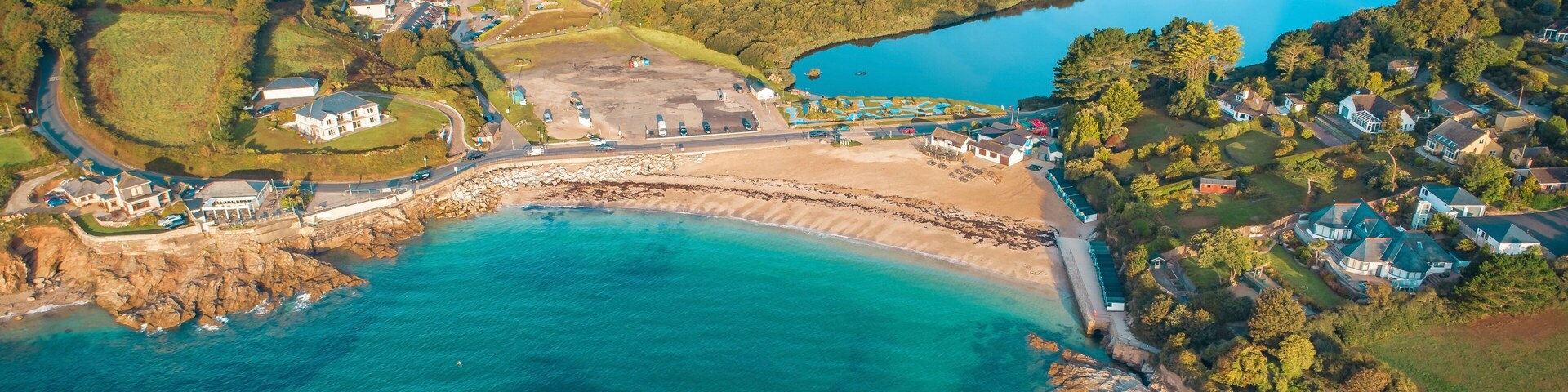 Vista aérea de un pueblo costero con playa, un lago grande y zonas residenciales.