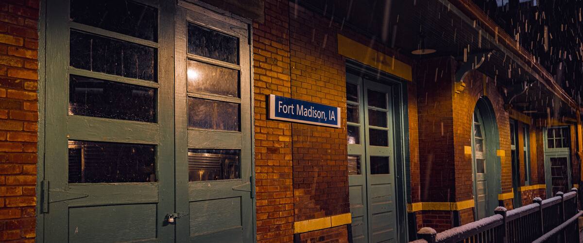 Un edificio de ladrillo con un letrero que dice "Fort Madison, IA" y puertas verdes.