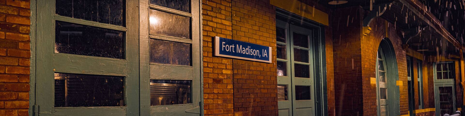 A brick building with a sign reading "Fort Madison, IA" and green doors.